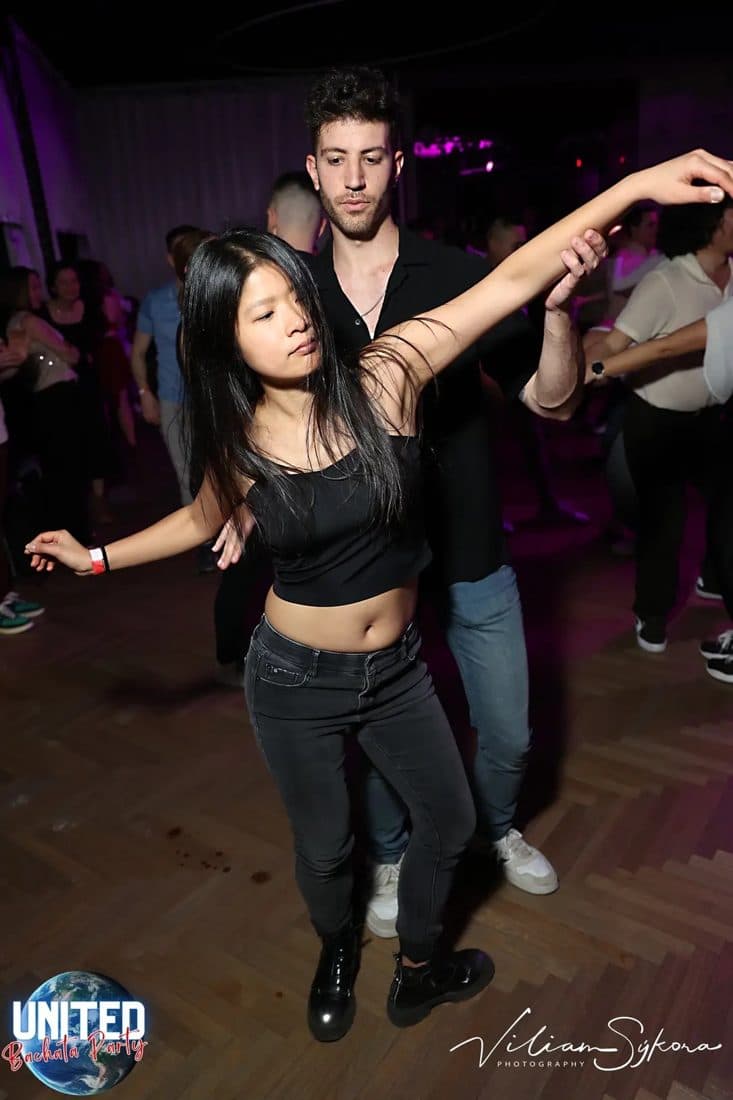 Shirley mid-turn on a crowded social dance floor, caught by the event photographer