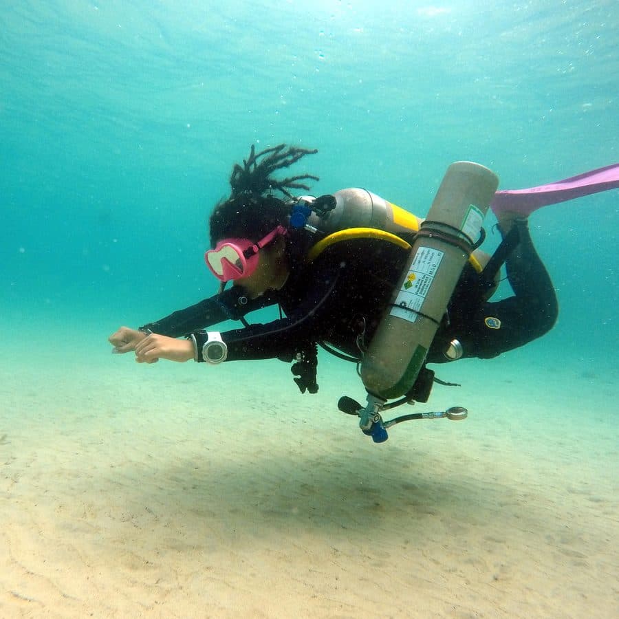 Shirley scuba diving over white sand — pink mask, pink fins
